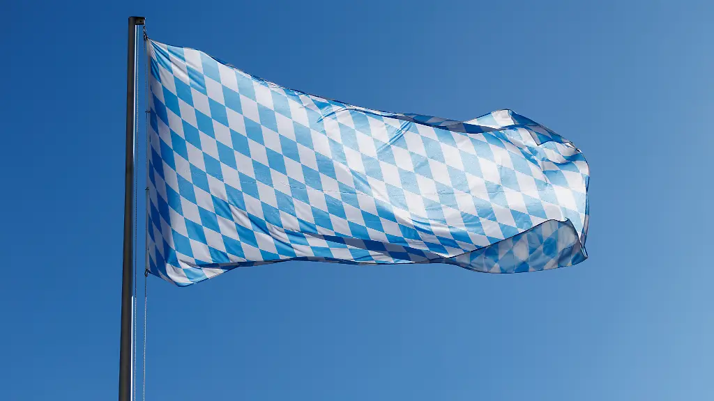 Un drapeau bavarois souffle au vent sur un mât devant le ciel bleu à Munich, en Bavière, le 18 mars 2025.